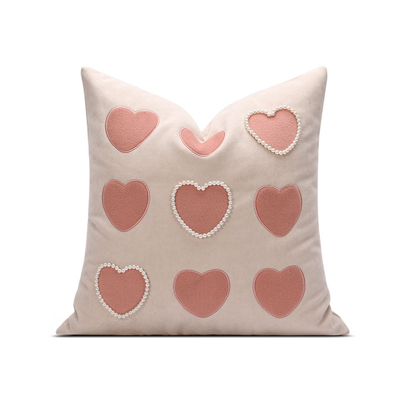 A light pink pillow with pink hearts on it.