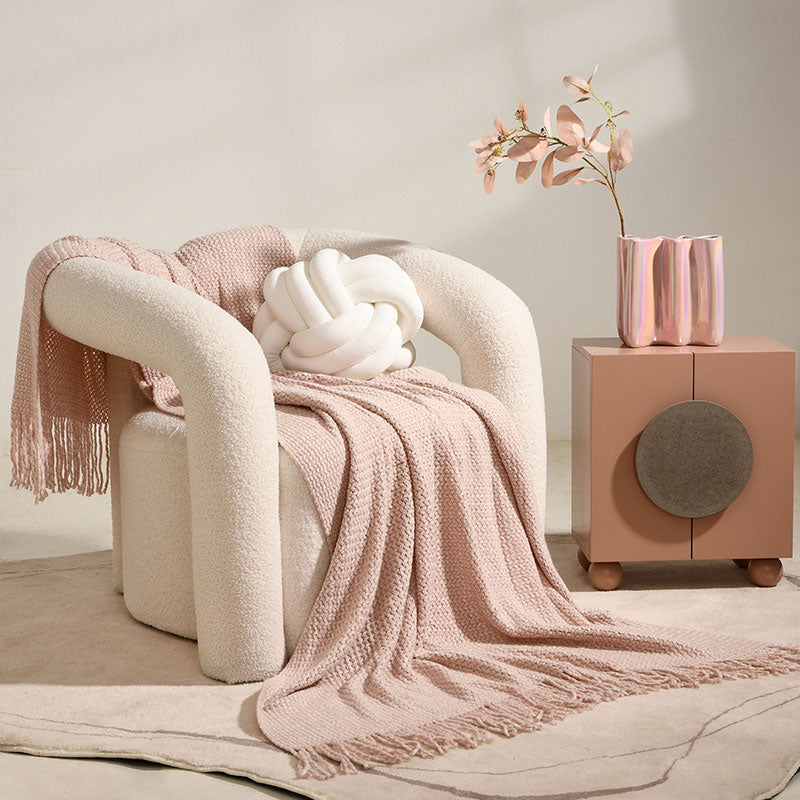 A chair with a blanket and a pink blanket on it.