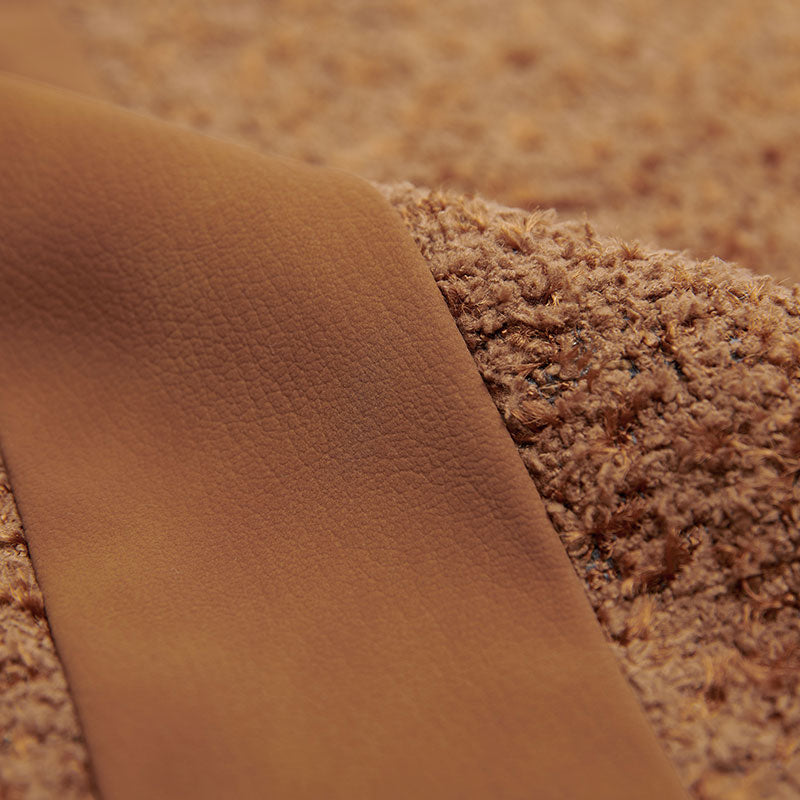 A rust brown pillow with a leather strip