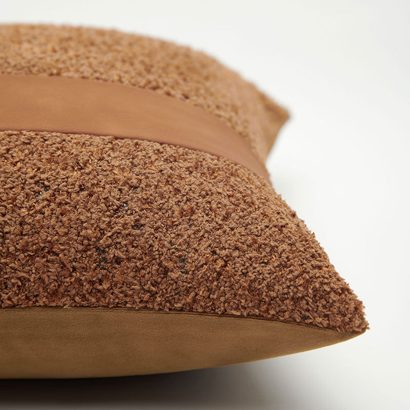 A rust brown pillow with a leather strip